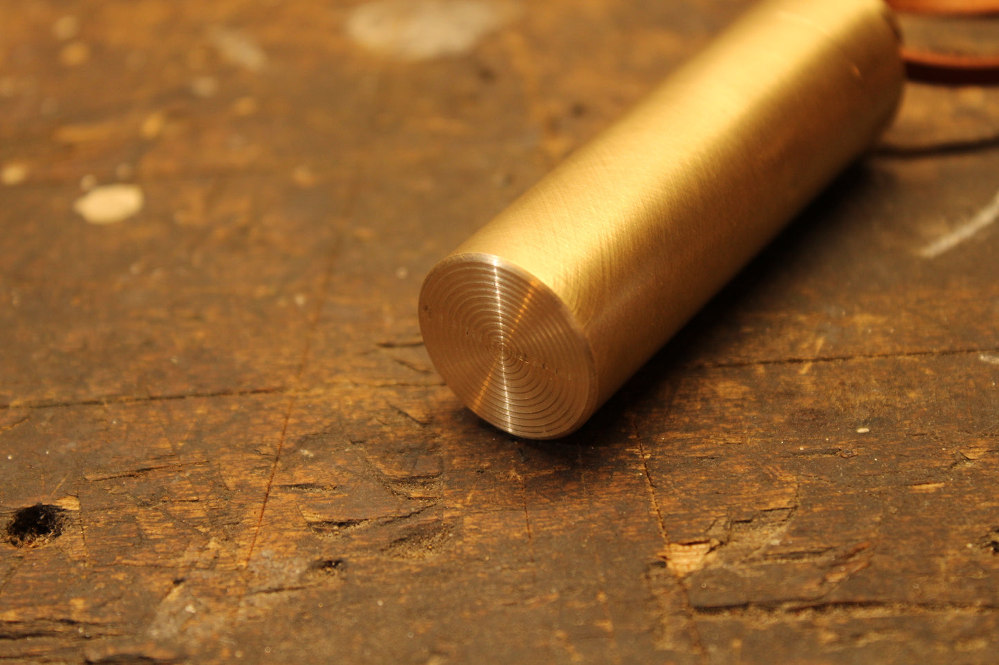 Textured bottom of brass strike anywhere match holder on wood work bench