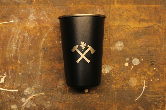 Matte black stainless steel cup with Oak and Anvil logo on wood work bench 