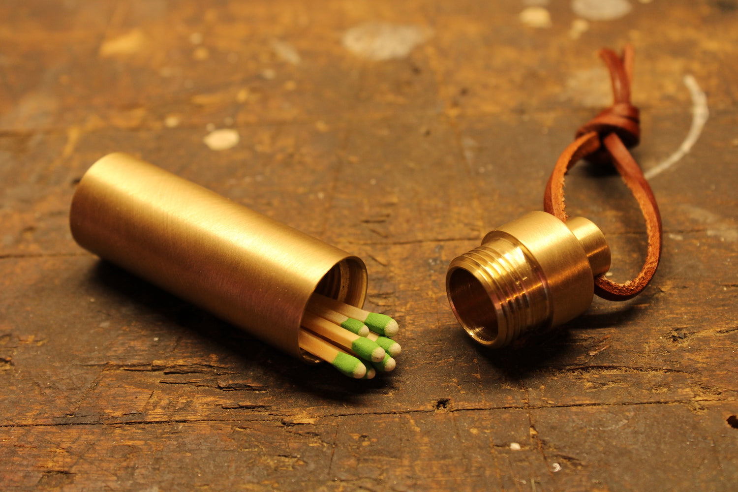 Open brass match holder containing strike anywhere matches on wood work bench