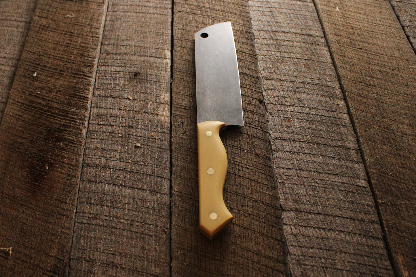 Chef's knife with stone washed blade and antique ivory micarta handle on wood